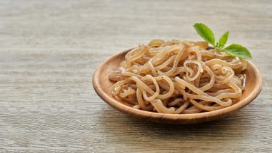 concepto de ensalada de fideos konjac marrones y hojas verdes en un plato de madera sobre