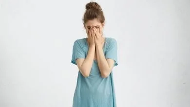 mujer desanimada decepcionada con moño de pelo vistiendo una camiseta suelta decepción