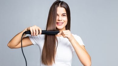 mujer joven sonriente que se endereza el pelo con blanco